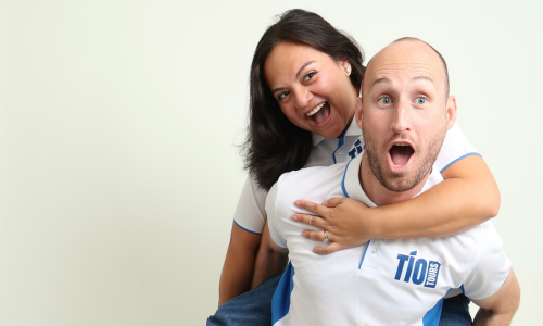  Emely Barahona and her partner pose piggyback and wear their Tio Tours shirts.