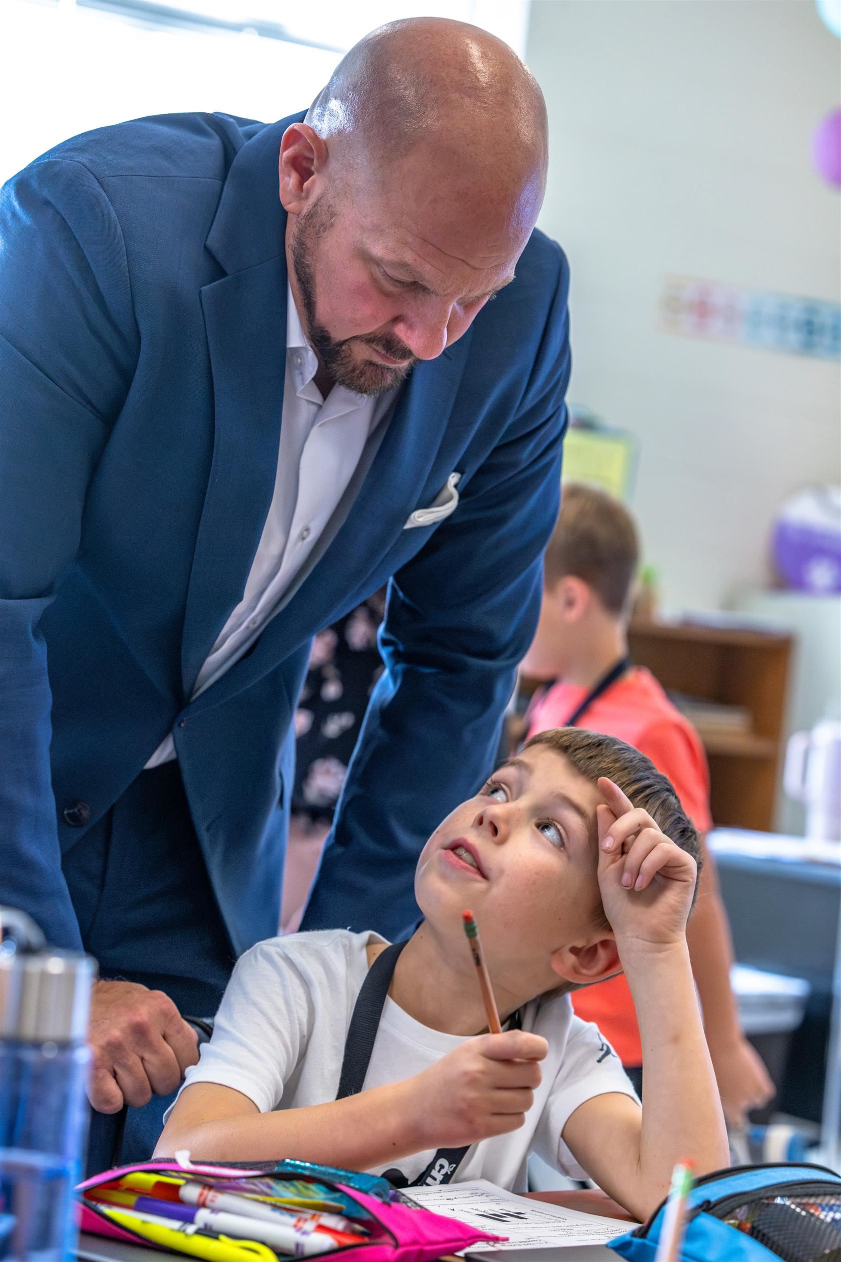 Grand Oak Elementary principal stands above young student 