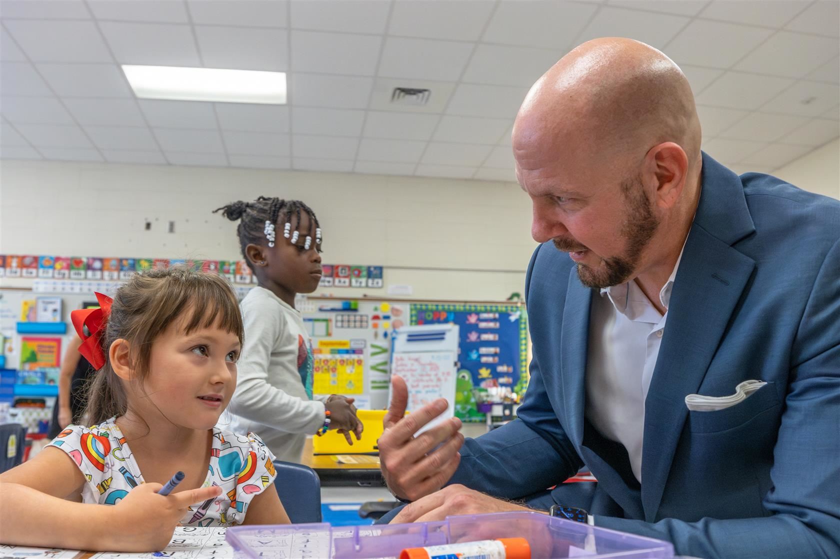 Grand Oak Elementary principal sits with a young student at a table