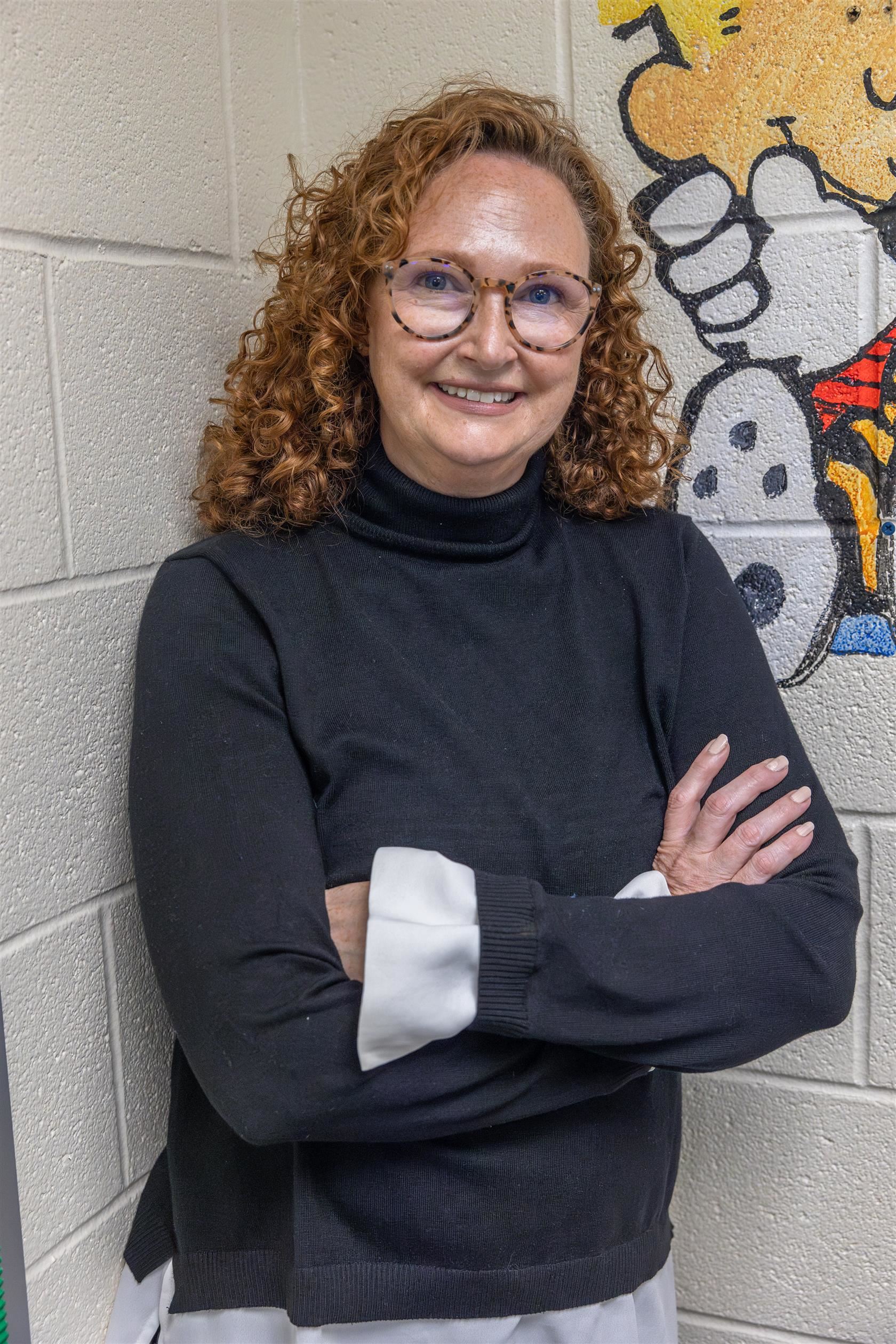 Coulwood STEM Principal Dr. Janet Moss smiles in front of a cartoon drawing on wall