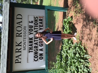 Young Alyssa Peterson posing in front of Park Road Montessori's sign. 