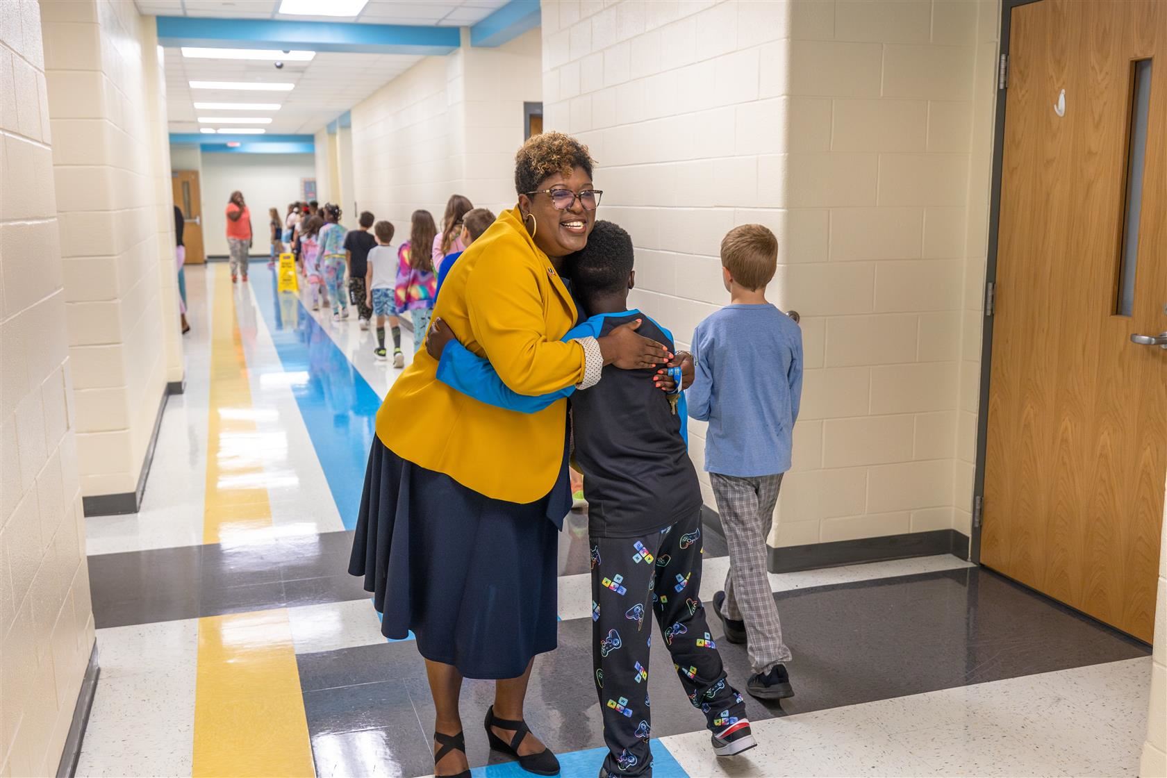 NAWL Principal Lydia Fergison hugs a student in the hallway.