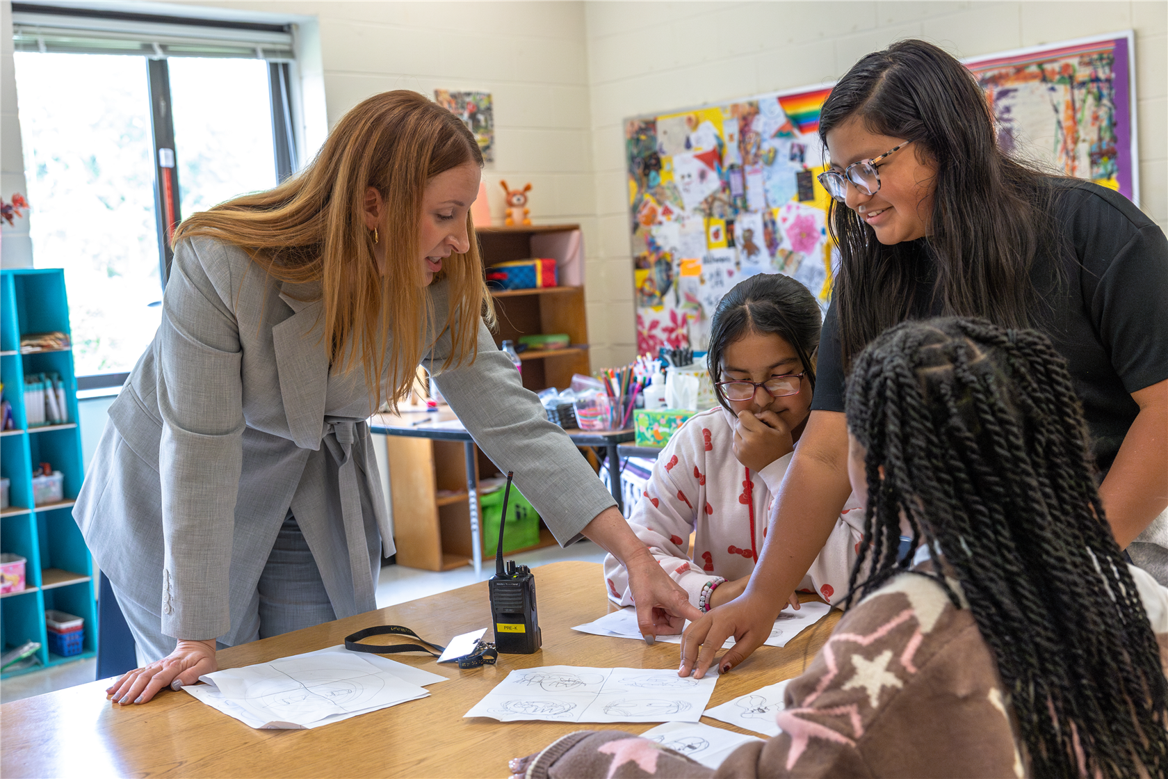 Principal Polite showing something to three students in the classroom.