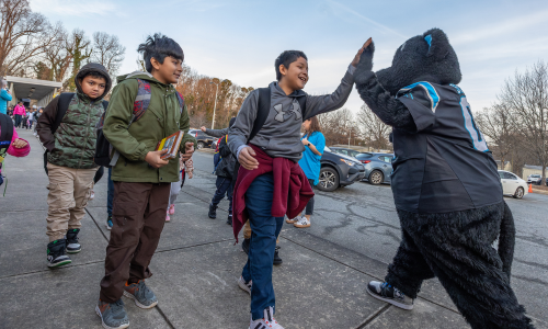  Merry Oaks International Academy student high fives Sir Purr on the way into school