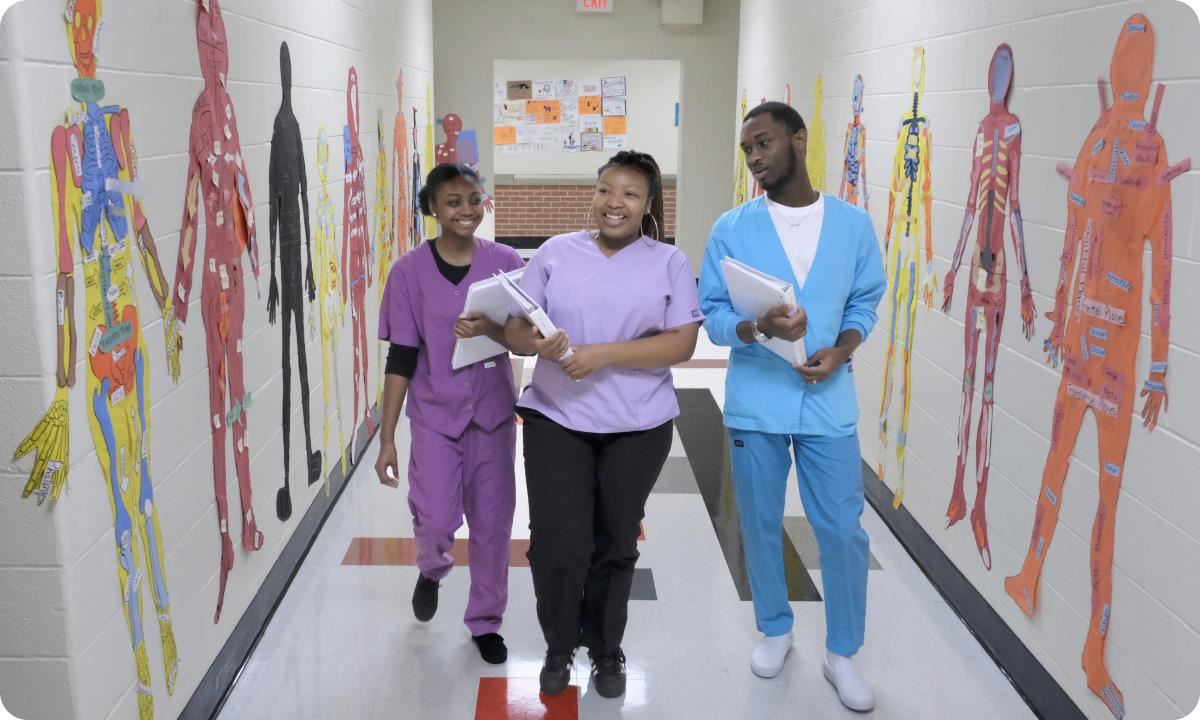 Students wearing scrubs in school hallway.